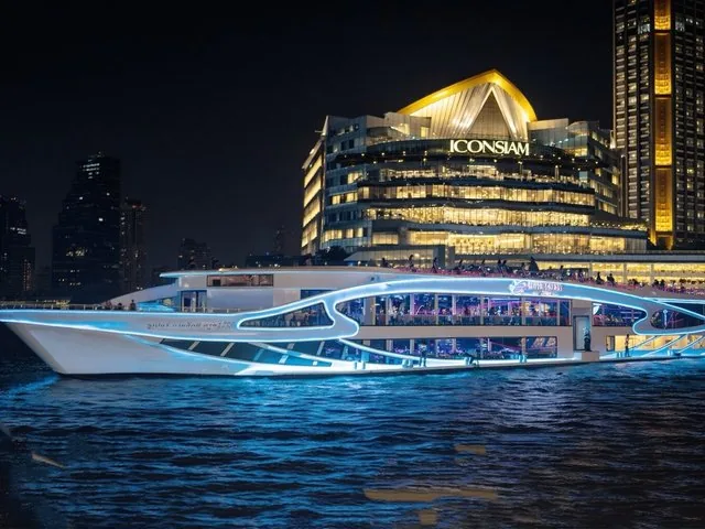 Ein modernes Dinner-Cruise-Boot mit blauen Lichtern bei ICONSIAM bei Nacht.