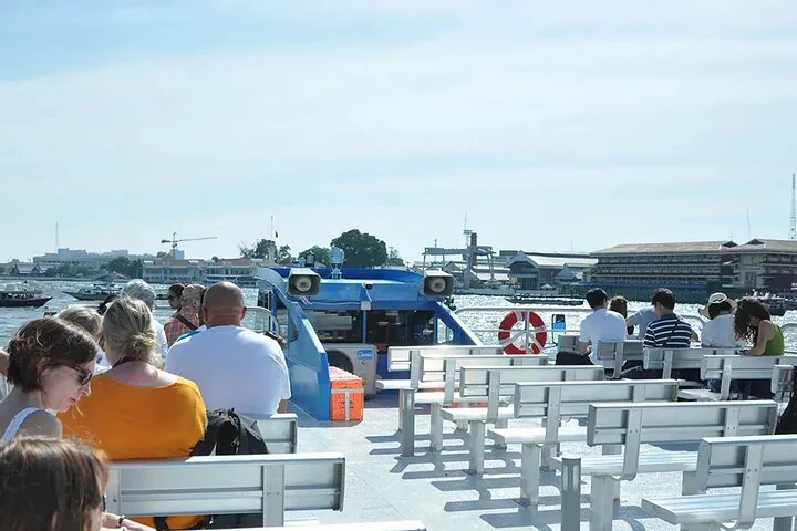 Pasajeros sentados en la cubierta superior descubierta de un barco turístico en Bangkok.